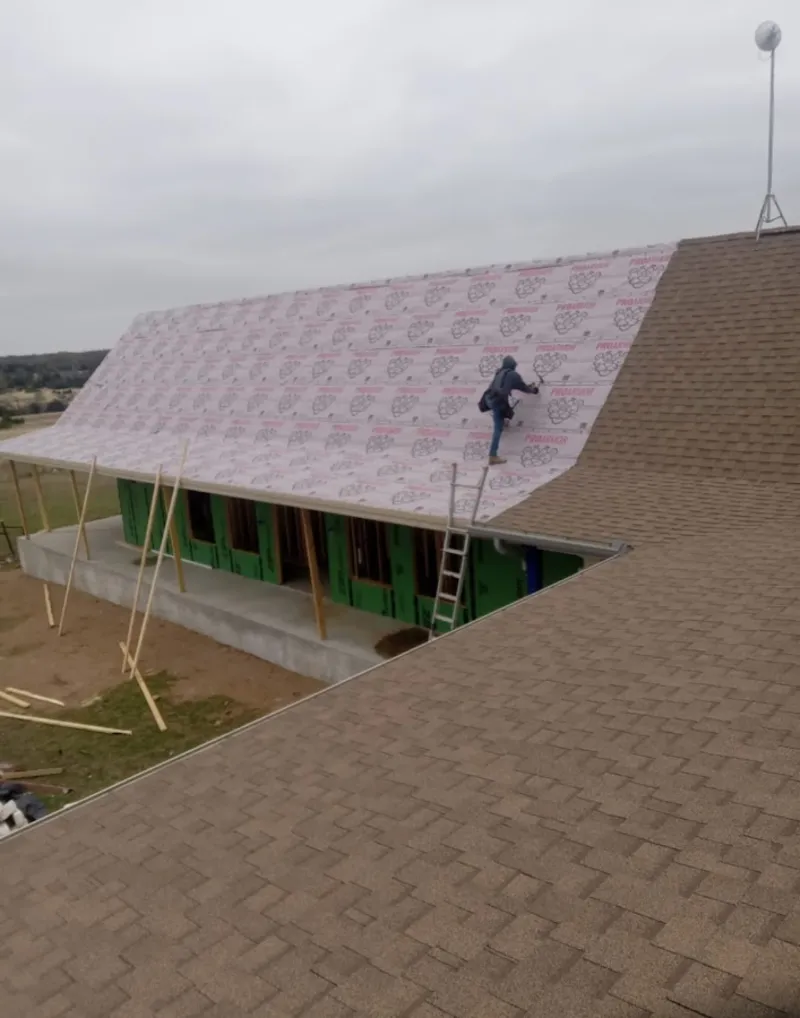 Worker preparing underlayment for a metal roof installation in Port Neches